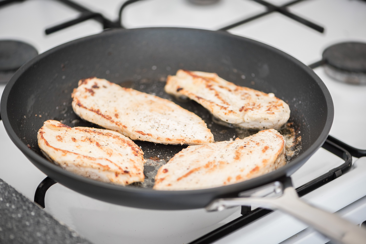 Foto van kipfilet die wordt gebraden in een pan