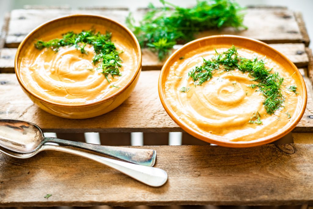 Liggende foto van gazpacho meloen met lepels en garnituur